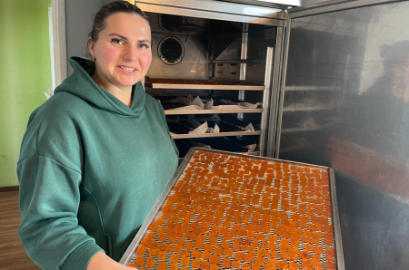 Dienu un nakti mājas virtuvē darbojas žāvētava. Attēlā: saimniece no žāvētavas izņem kārtējo gatavo konfekšu plāti.