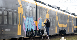 Vīrietis mazgā ar grafiti apķēpātu jauno "Škoda Vagonka" elektrovilcienu Vagonu depo.