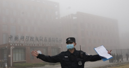 Ķīnas drošībnieks attur žurnālistus no tuvošanās Viroloģijas institūtam Uhaņā, kur 2021. gada februārī bija ieradusies Pasaules veselības organizācijas ekspertu grupa.
