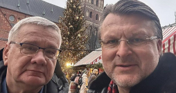 Partijas "Latvija pirmajā vietā" līderis Ainārs Šlesers (no labās) aizvadītā gada nogalē ievietoja soctīklos pašbildi, kurā redzams kopā ar Jāni Lāčplēsi Ziemassvētku tirdziņā Doma laukumā.