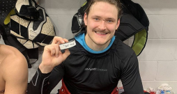 Smaidīgais Eduards Tralmaks pozē ar ripu pēc spēles, kurā viņš pirmo reizi savā profesionālajā karjerā Ziemeļamerikā guva trīs vārtus.