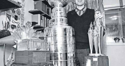 Toronto Hokeja slavas zāles kurators Moriss Reids pozē ar 1970. gadā nozagtajām un atgrieztajām trofejām – Kona Smaita balvu (no kreisās), Stenlija kausu un Billa Mastertona balvu.