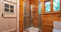 Guļbūvē ierīkota duškabīne ar stikla sienām.