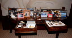 Epstīna faili. 
Fotogrāfijā redzams galds ar atvērtu atvilktni, kur atrodas kaudzīte ar fotogrāfijām, tai skaitā foto, kur Tramps ir kopā ar bikini tērptām sievietēm. Šis Trampa foto uzņemts pirms viņš kļuva par prezidentu.