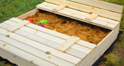 Smilškaste ar vāku, kas pārtop par soliņu.