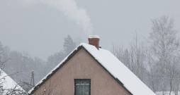 Māja ar kūpošu skursteni ziemā.
