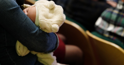 Zīdainis vecāka rokās.