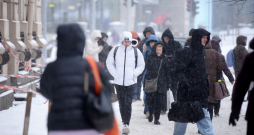 Cilvēki sniegputeņa laikā Merķeļa ielā.