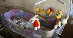 Lelle bērnu gultiņā.