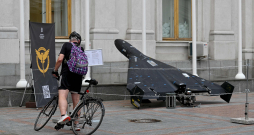 Vīrietis lasa informatīvu stendu pie Irānā ražota bezpilota lidaparāta Shahed 136 (Geranium-2), kas izstādīts pie Ukrainas Ārlietu ministrijas ēkas Kijivā 2025. gada 21. jūlijā Krievijas iebrukuma Ukrainā laikā.