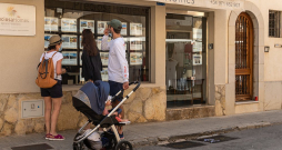 Tūristi Maļorkas (Spānija) pilsētā Kamposā pēta nekustamo īpašumu firmas skatlogā izlikto mājokļu piedāvājumu.