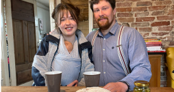 Ellena un Gunārs ar savu pirmdzimto lielajā istabā, kur uz brokastu galda
ir arī saimnieka cepta maize.