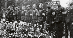 Bijušo Latvijas armijas karavīru un aizsargu – tobrīd Vācijas kārtības
dienesta darbinieku ierinda  pie padomju okupācijas Baigā gada
upuru masu kapa. 1941. gada vasara.