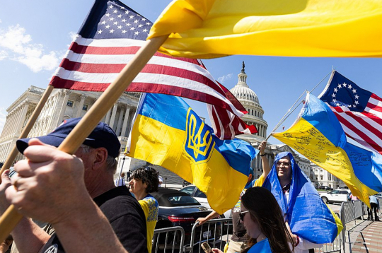 Ukrainas atbalstītāji ar karogiem pie Kapitolija ēkas priecājas par ASV Kongresa Pārstāvju palātas lēmumu.