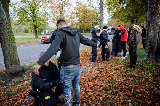 Vācijas Federālās policijas (Bundespolizei) darbinieki pārmeklē grupu migrantu pie Forstas, Austrumvācijā. Vācijas Federālās policijas (Bundespolizei) darbinieki pārmeklē grupu migrantu pie Forstas, Austrumvācijā.