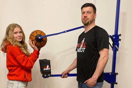 Jānis Gremzde ar meitu Skārletu pie basketbola metiena trenažiera.