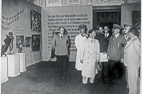 Hitlers Deģeneratīvās mākslas izstādē Minhenē. No Hitlera pa labi – profesors Cīglers un Heinrihs Hofmans, pa kreisi Haušs, Gebelss u. c. 1937. gada 19. jūlijs.