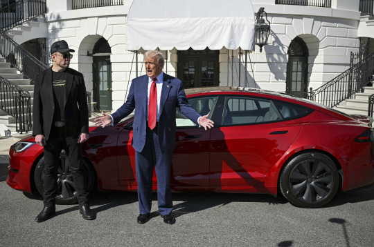 Prezidents Donalds Tramps un "Tesla" izpilddirektors Īlons Masks runā ar reportieriem pie sarkanas "Tesla Model S" automašīnas Baltā nama Dienvidu zālienā, otrdien, 2025. gada 11. martā, Vašingtonā.