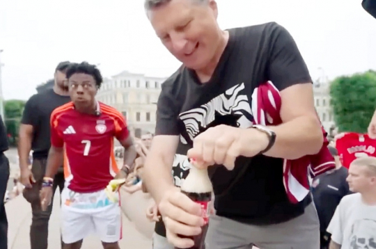 Kad Raimonds Vējonis mēģina attaisīt kolas pudeli, tās saturs izšļakstījās, atstājot uz pieminekļa traipus.