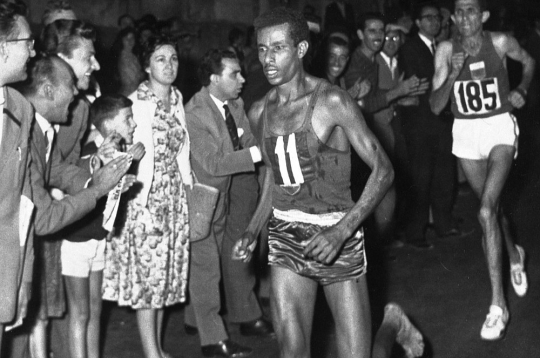 Baskājainais Abebe Bikila Romas olimpiskajā maratonā priekšā marokānim Rhadi ben Abdesalamam. Etiopietis kļuva par pirmo un vienīgo skrējēju moderno olimpisko spēļu vēsturē, kurš maratonā uzvarējis, skrienot bez apaviem.