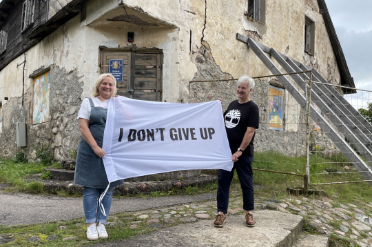 Ieva un Dainis Grozas pie Lēdurgas kroga ieejas ar plakātu, kura teksts angļu valodā vēsta “Es nepadošos”. Esot aizgūts no mākslinieka Kristiana Brektes oriģināla.