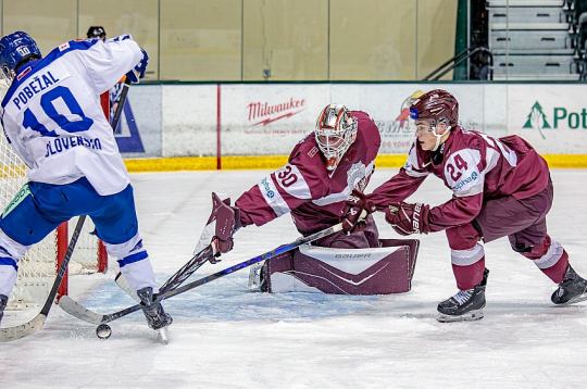 Latvijas junioru izlases vārtsargs Nils Mauriņš un uzbrucējs Daniels Serkins pārbaudes spēlē pret Slovākiju cenšas nosargāt savu vārtu drošību.
