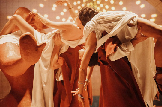 Dejotāju–aktieru – ķermeņi savijas jutekliskā rituālā ap erotiskām skulptūrām.