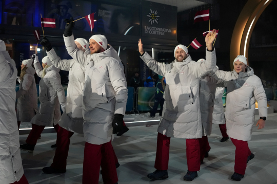 Latvijas karognesējs 2026. gada ziemas olimpiskajās spēlēs, hokejists Kaspars Daugaviņš (no labās) un Latvijas delegācijas sportisti 2026. gada Milānas un Kortīnas ziemas olimpisko spēļu atklāšanas ceremonijā "San Siro" stadionā Milānā, Itālijā.