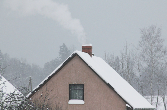Māja ar kūpošu skursteni ziemā.
