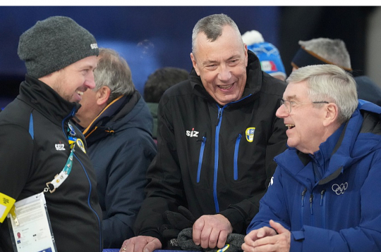 Bijušo Starptautiskās olimpiskās komitejas prezidentu Tomasu Bahu (no labās) izklaidē latvieši – Starptautiskās kamaniņu sporta federācijas prezidents Einars Fogelis un agrāk titulētais kamaniņnieks, šobrīd starptautiskās federācijas mākslīgās ledus trases tehniskais direktors Andris Šics.