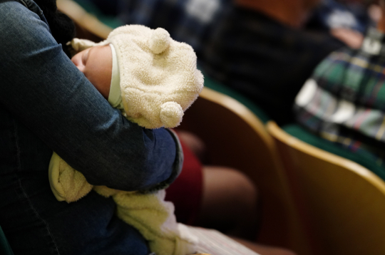 Zīdainis vecāka rokās.