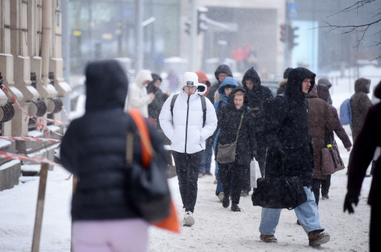 Cilvēki sniegputeņa laikā Merķeļa ielā. Cilvēki sniegputeņa laikā Merķeļa ielā.