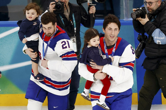 ASV izlases hokejisti Dilans Larkins (no kreisās) un Zaks Verenskis ar traģiski bojā gājušā bijušā komandas biedra Džonija Gudro bērniem pirms čempionu kopbildes.