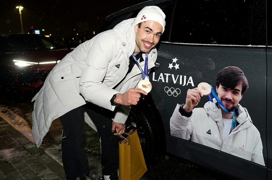 Olimpiskais medaļnieks Roberts Krūzbergs pozē pie mašīnas ar olimpiskā medaļnieka bildi uz tās. Šorttrekists atzīst, ka tik lielu uzmanību no apkārtējiem izbauda pirmo reizi dzīvē. Olimpiskais medaļnieks Roberts Krūzbergs pozē pie mašīnas ar olimpiskā medaļnieka bildi uz tās. Šorttrekists atzīst, ka tik lielu uzmanību no apkārtējiem izbauda pirmo reizi dzīvē.