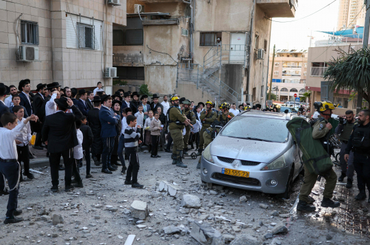 Izraēlas pirmās palīdzības dienestu darbinieki ierodas vietā, kur Telavivas piepilsētas rajonā 2026. gada 28. februārī nokritušas raķešu pārtveršanas laikā radušās atlūzas.