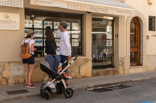 Tūristi Maļorkas (Spānija) pilsētā Kamposā pēta nekustamo īpašumu firmas skatlogā izlikto mājokļu piedāvājumu.
