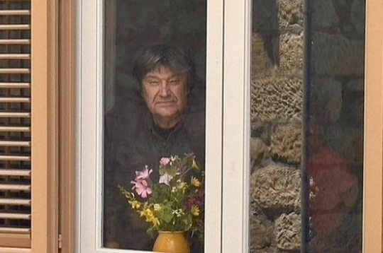 Jānis Lūsēns pie mājas virtuves loga.