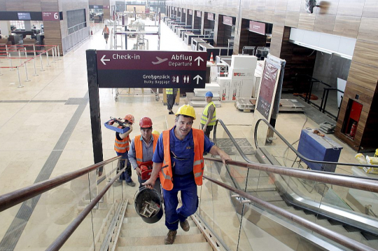Celtnieki Berlīnes-Brandenburgas lidostas iekštelpās. Lidostu atklāja 2020. gadā, taču tās būve vēsturē palikusi kā "katastrofa visos līmeņos".