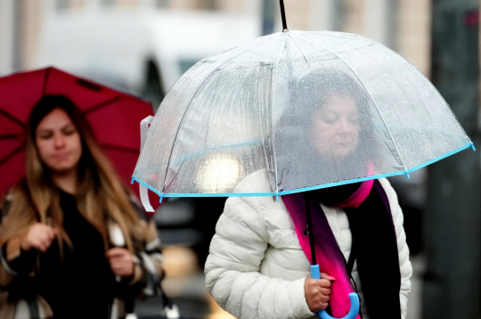 Cilvēki lietus laikā Rīgā.
