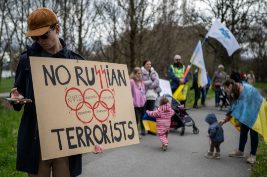 Šveices pilsētā Lozannā pie Starptautiskās Olimpiskās komitejas mītnes Ukrainas atbalstītāji protestē pret Krievijas sportistu līdzdalību starptautiskās sacensībās. Plakāts vēsta “Nē krievu
teroristiem”.