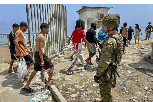 Spānijas karavīrs noraugās, kā no Marokas puses atpeldējušie migranti 31. jūlijā ierodas Seutā.