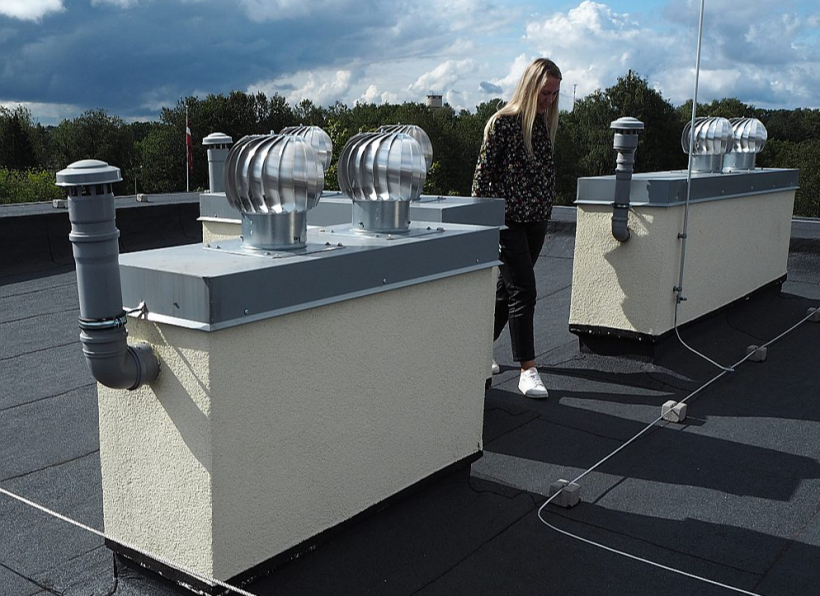 Rotējošs jumta deflektors un tualetes ventilācijas autonoma izeja uz renovētas daudzdzīvokļu ēkas jumta Valkā.