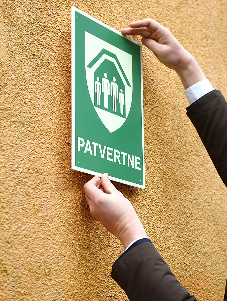 Droša patvēruma vietas, kas piemērotas iedzīvotāju pasargāšanai katastrofu un militāra apdraudējuma gadījumā, marķētas ar šādu zīmi.