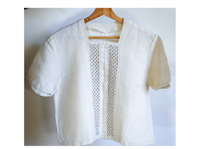 Blūze šūta no balta kokvilnas auduma ar izvilkuma tehnikā izšūtām slejām (TNMM 28600).