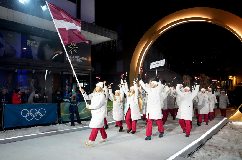 Latvijas karognesējs 2026. gada ziemas olimpiskajās spēlēs, hokejists Kaspars Daugaviņš (no labās) un Latvijas delegācijas sportisti 2026. gada Milānas un Kortīnas ziemas olimpisko spēļu atklāšanas ceremonijā "San Siro" stadionā Milānā, Itālijā.