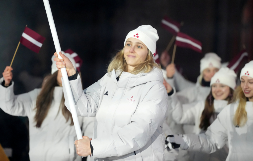 Latvijas karognesējs 2026. gada ziemas olimpiskajās spēlēs, hokejists Kaspars Daugaviņš (no labās) un Latvijas delegācijas sportisti 2026. gada Milānas un Kortīnas ziemas olimpisko spēļu atklāšanas ceremonijā "San Siro" stadionā Milānā, Itālijā.