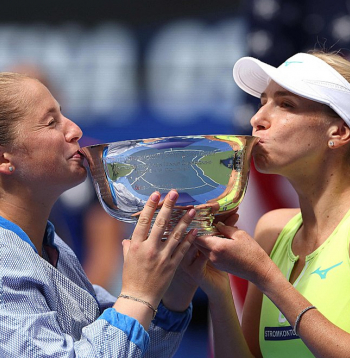 Aļona Ostapenko (no kreisās) un Ludmila Kičenoka ar ASV atklātā čempionāta dāmu dubultspēļu turnīra galveno trofeju.
