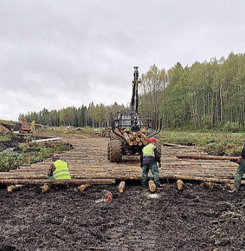 Uz garenvirzienā izvietotiem baļķiem pamīšus tiek klāti sīkbaļķi, noslēgumā konstrukcija tiks iekūdrota ar turpat iegūto kūdru.