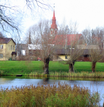 Aiz Dzirnavu ezera pakalna panorāmā redzama Lēdurgas Ev. luteriskā baznīca.