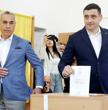 Rumānijas prezidenta amata kandidāts Džordže Simions (no labās) svētdien vēlēšanu iecirknī ieradās kopā ar pērnā gada anulēto vēlēšanu pirmās kārtas uzvarētāju Kelinu Džordžesku.